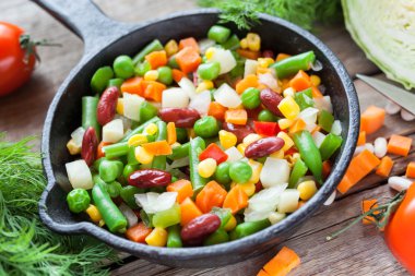 Mixed vegetables in retro frying pan and ingredients on wooden r clipart
