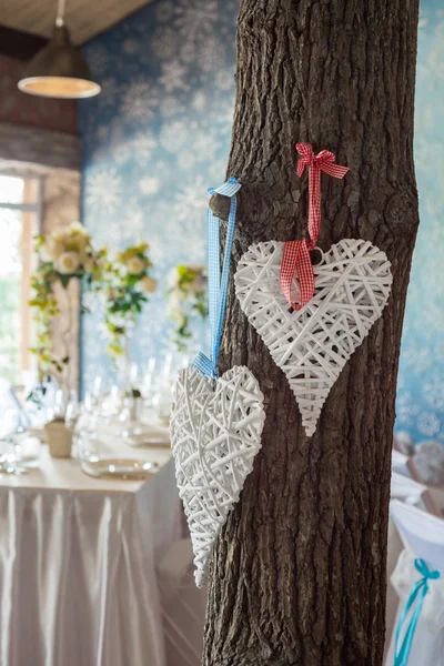 Two wicker hearts hanging on tree in wedding hall. — Stock Photo, Image