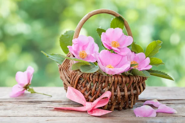 Rieten mand met wilde roze bloemen. Bruiloft of verjaardag decora — Stockfoto