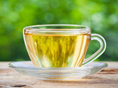 Tea cup on wooden table. Green background.