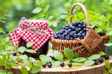 Jars of jam and basket with wild blueberries
