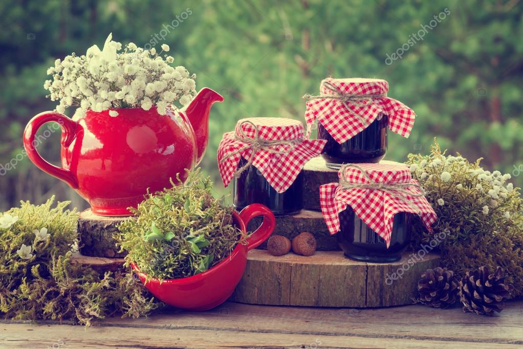 Red teapot, tea cup and jars of healthy jam. Wedding decorations