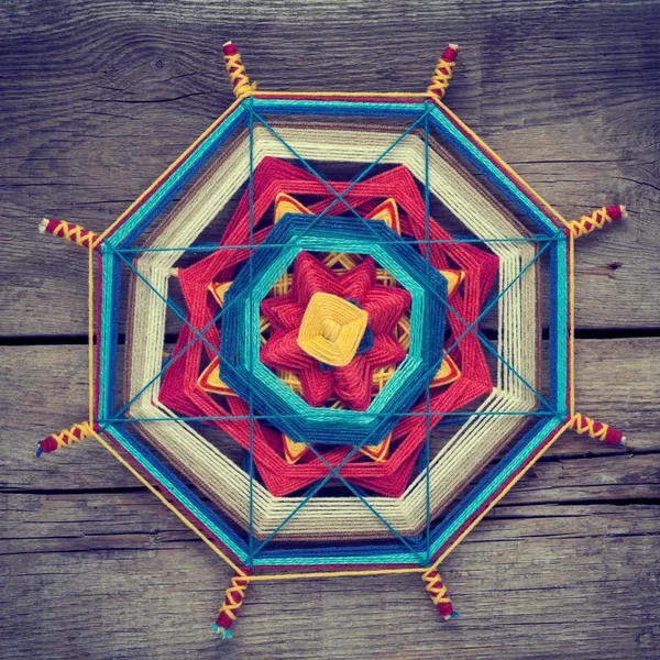 Knitted tibetan mandala from threads on old wooden background — Stock Photo, Image