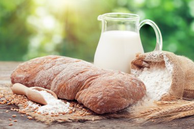 Taze ekmek, sürahi süt, un ve buğday kulaklara ahşap çuvalı