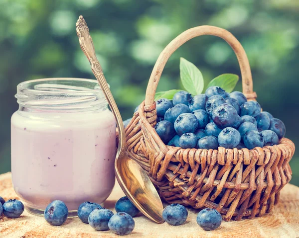 Yogur de arándanos frescos en tarro de vidrio y canasta de mimbre con bil —  Fotos de Stock