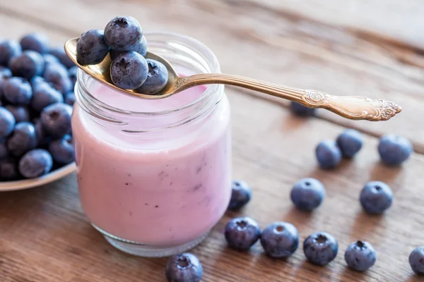 Yogur de arándanos frescos en frasco de vidrio, cuchara y platillo de bilbo —  Fotos de Stock