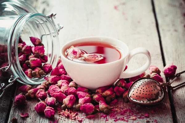 玫瑰芽茶叶、 茶杯、 过滤器和玫瑰花蕾的玻璃罐。Se — 图库照片