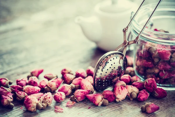 Té de capullos de rosa, primer plano del colador de té, tarro de vidrio y tetera en bac — Foto de Stock