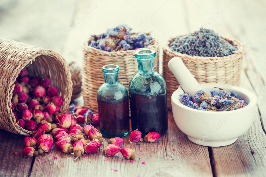 Bottles of tincture, basket with rose buds, lavender and dried f