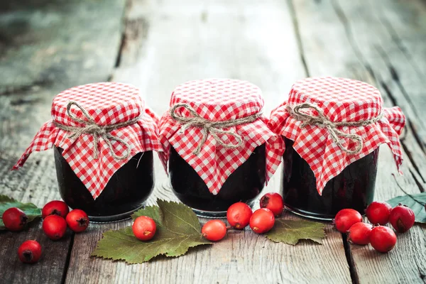 Three jars of jam and hawthorn berries on rustic table — Stock Photo, Image