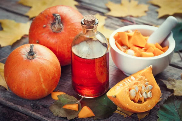 Botella de aceite de semillas de calabaza, calabazas y mortero en mesa de madera wi —  Fotos de Stock