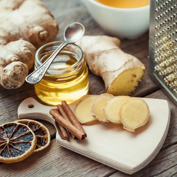 Jengibre en la tabla de cortar, tarro de miel, rodaja de limón seco, cinnam —  Fotos de Stock