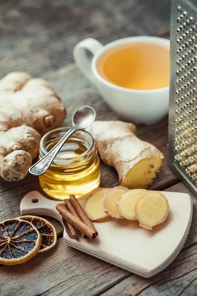 Gingembre sur planche à découper, pot de miel, tasse à thé et râpe sur kit — Photo