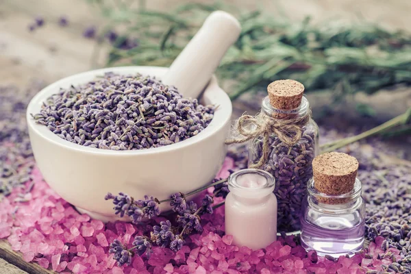 Lavender in mortar, sea salt, cream and bottles of oil and lavender — Stock Photo, Image