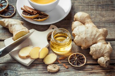 Zencefil kökü üzerinde kesme tahtası, kavanoz bal ve çay fincan dilimlenmiş