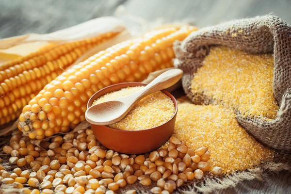 Corn groats and dry seeds, corncobs on wooden rustic table. — Stock Photo, Image