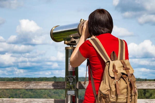 Woman looking through tourist telescope, exploring mountain landscape — Stock Photo, Image