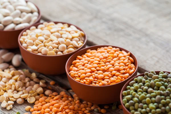 Cuencos de granos de cereales: lentejas rojas, mungo verde, maíz, frijoles y — Foto de Stock