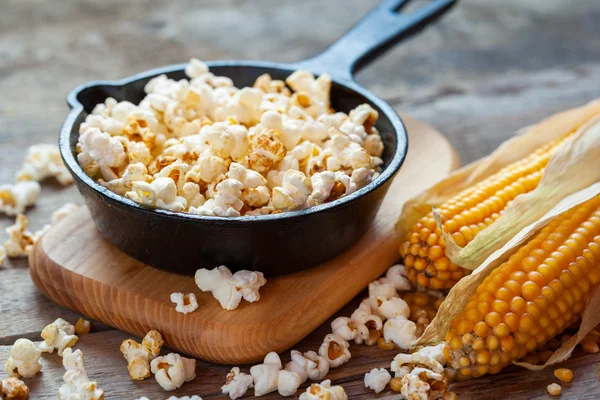 Bereid popcorn in koekenpan op cutting board en maïs zaden — Stockfoto