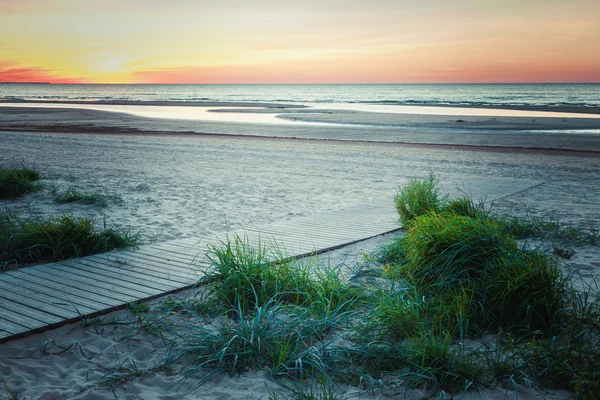 Houten wandelpad naar de zee bij zonsondergang. Retro stijl foto. — Stockfoto