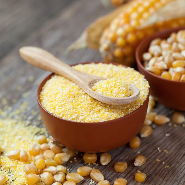 Havre gryn i skål, majs frön och corncobs på köksbordet. — Stockfoto