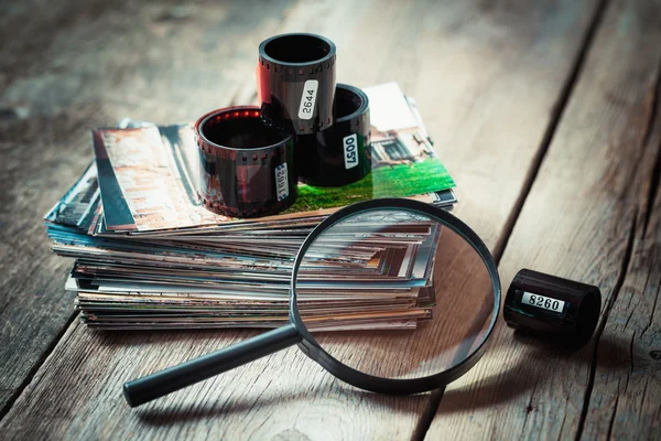 Photo film rolls, retro camera, stack of photos and magnifier — Stock Photo, Image