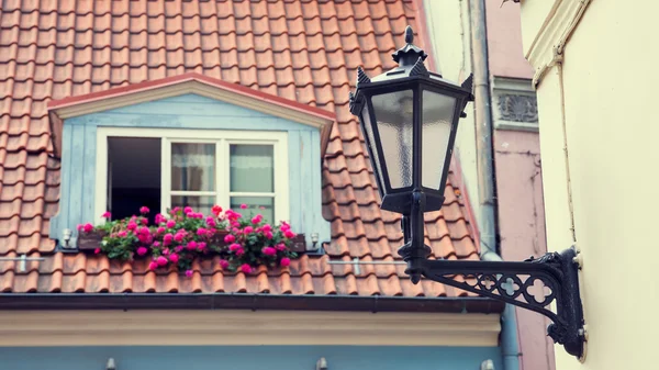 Винтажная уличная лампа на стене и окне в чердачной крыше — стоковое фото