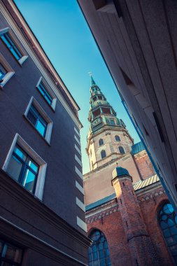 St Peters Church in old city Riga, Latvia. View from narrow street. clipart