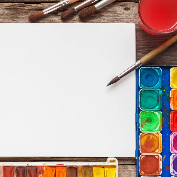 Juego de acuarelas, pinceles y papel blanco en blanco — Foto de Stock