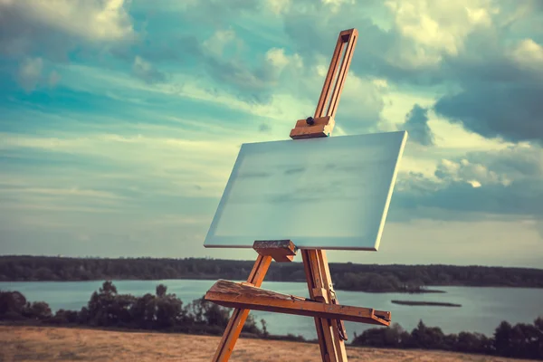 Blank canvas rests on a easel on lake landscape — Stock Photo, Image