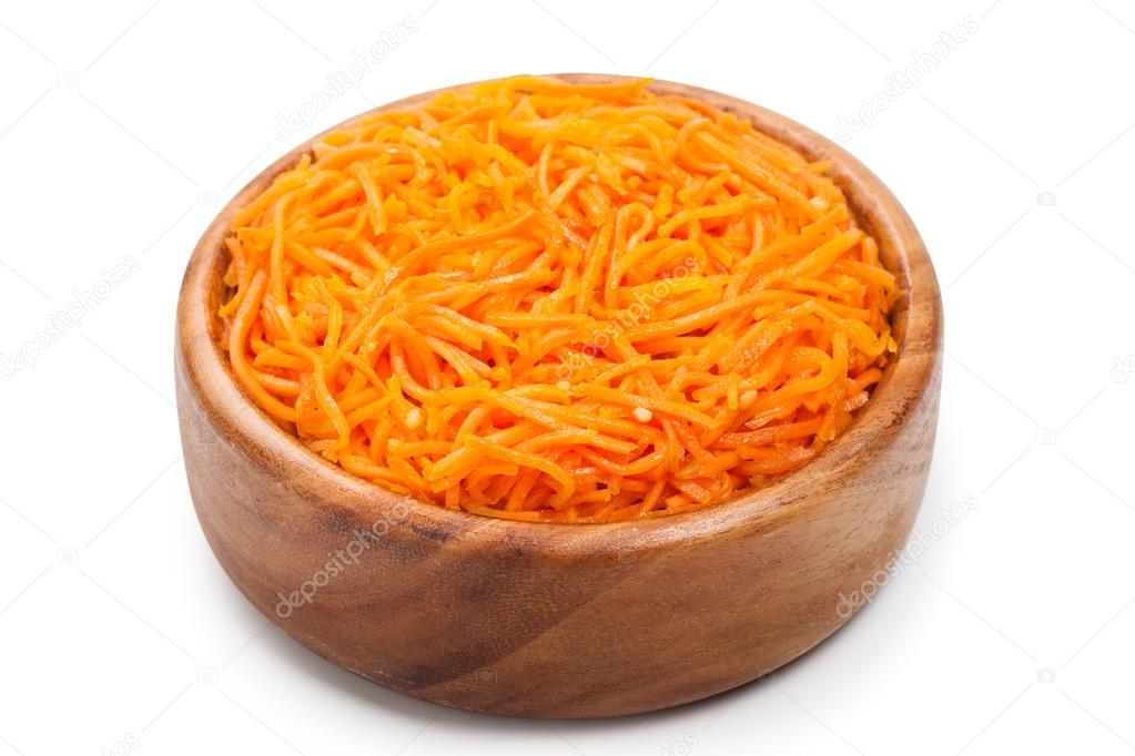Grated carrots. Korean salad in wooden bowl on white.