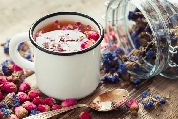 Rose buds tea in tea cup and glass jar of forget me not flowers. — Stock Photo, Image