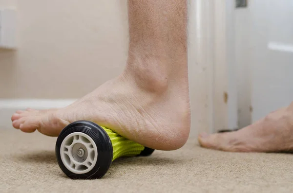 Plantar Fasciitis. Tedavi için evde ayak silindiri kullanan bir hasta..