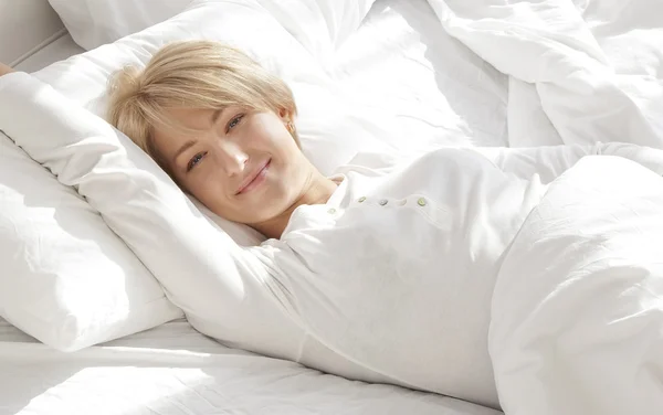 sabah, beyaz bir yatakta güzel kız gülümseyerek