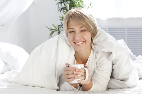 Vacker flicka på morgonen i sängen med kopp — Stockfoto