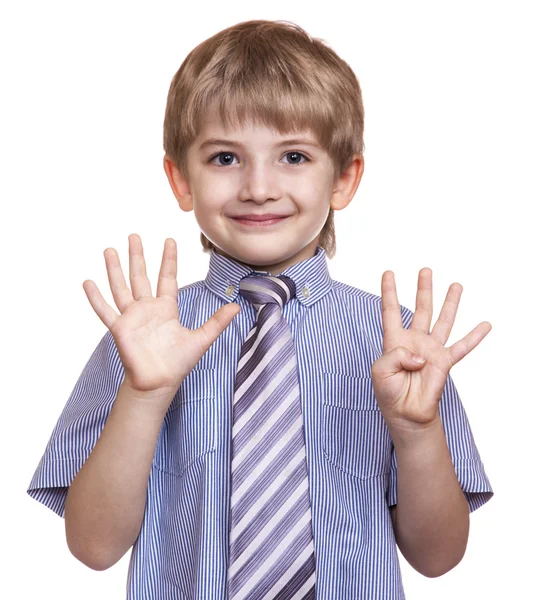 Niño sonriente muestra nueve dedos sobre un fondo blanco —  Fotos de Stock