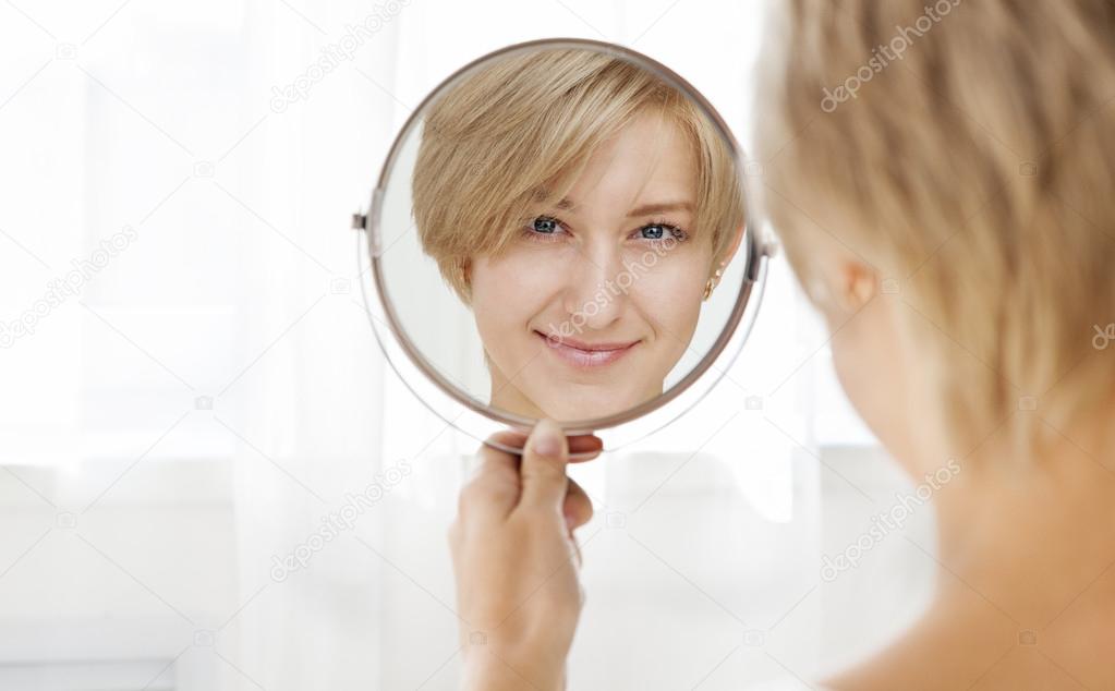 Beautiful healthy young woman looking in the mirror
