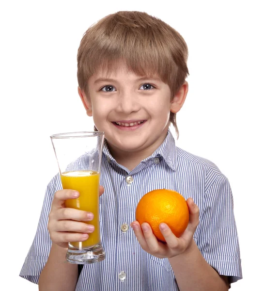 Cute caucasian boy holding a glass of orange juice and orange — Stock Photo, Image