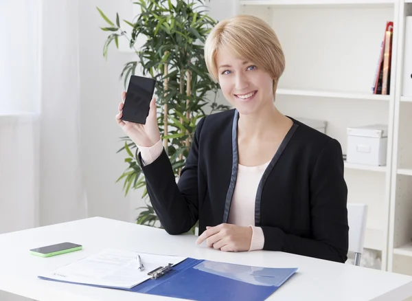 Schöne Geschäftsfrau im Büro zeigt den Smartphone-Skandal Stockbild