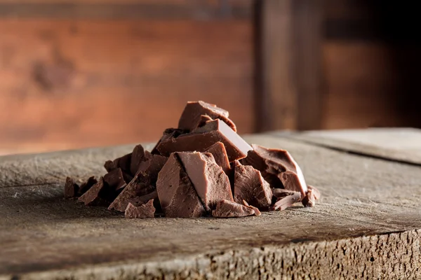 Stukken van melkchocolade op hout — Stockfoto