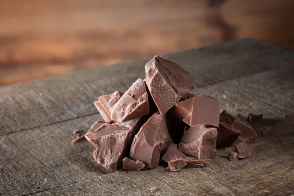 Stukken van melkchocolade op hout — Stockfoto