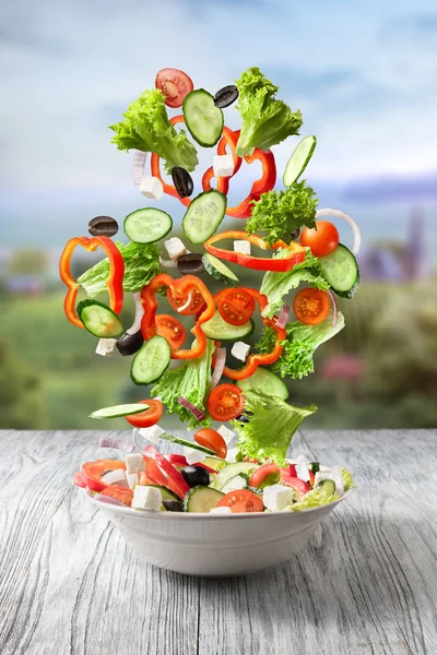 Legumes frescos misturados caindo em uma tigela de salada — Fotografia de Stock