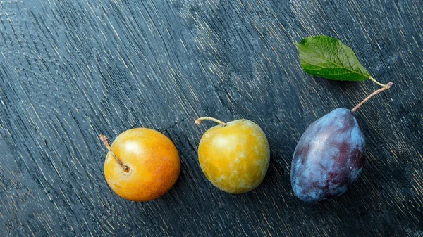 Tres ciruelas sobre un fondo negro — Foto de Stock