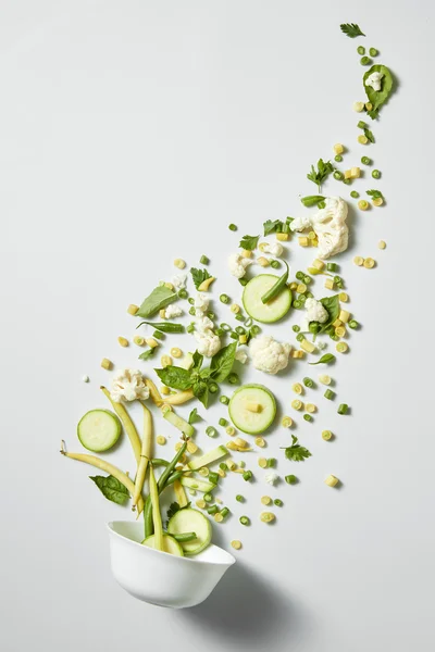 Salada de legumes verde fresca voando de uma tigela — Fotografia de Stock