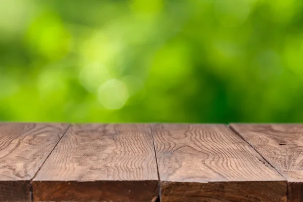 Leerer Holztisch vor grünem Hintergrund — Stockfoto