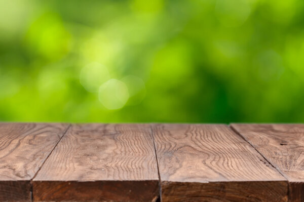 Empty wooden table against green background