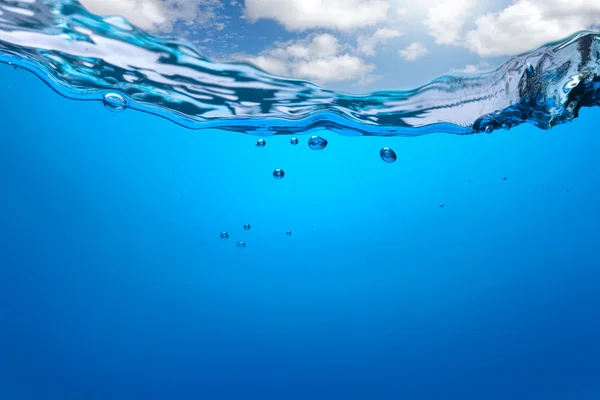 Всплеск голубой воды с пузырями и голубым небом — стоковое фото