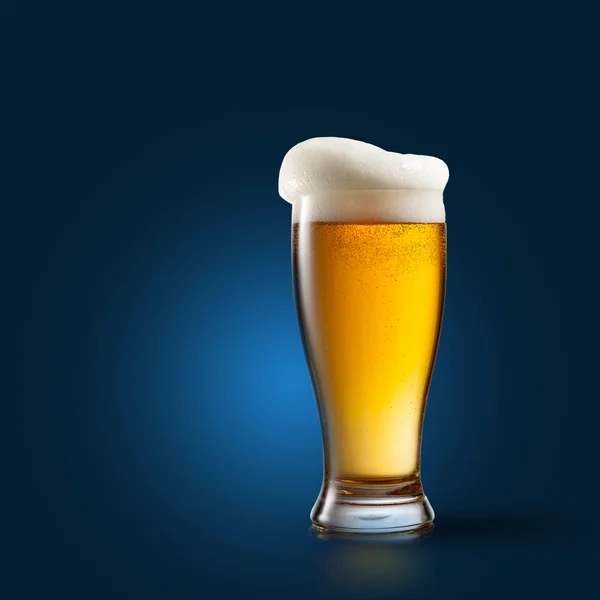 Пиво в стакане на голубом — стоковое фото