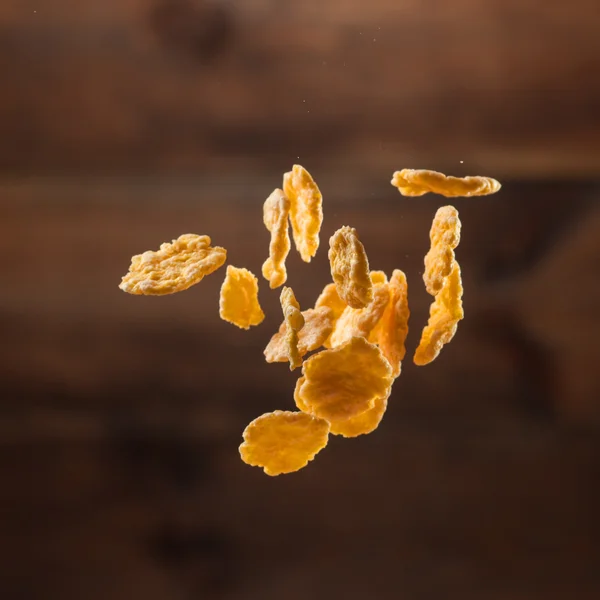 Fallende Cornflakes auf hölzernem Hintergrund — Stockfoto