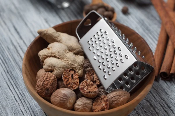 Ginger with nutmeg and grater in bowl on wooden background — Stock Photo, Image